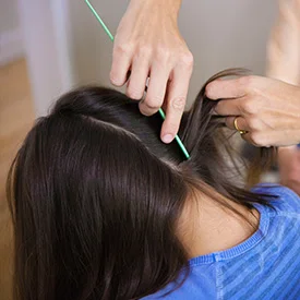 Young girl getting her hair combed through checking for lice