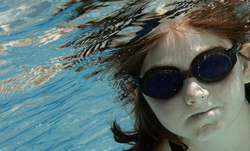 Girl wearing goggles underwater in a swimming pool