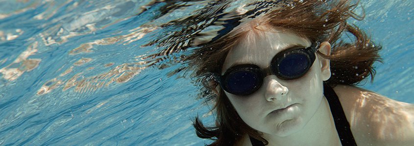 Girl wearing goggles underwater in a swimming pool