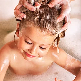 girl in the bath tub getting her hair washed for lice treatment