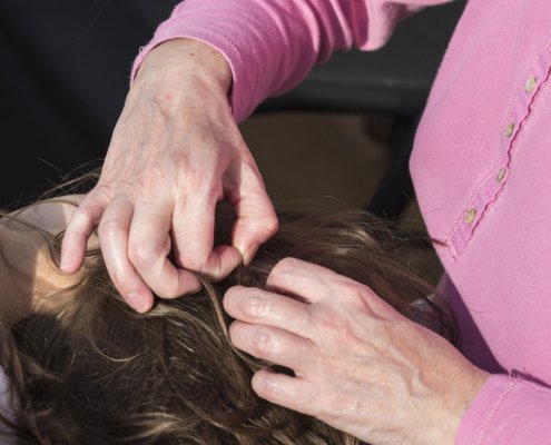 Woman picking through her daughters hair looking for lice