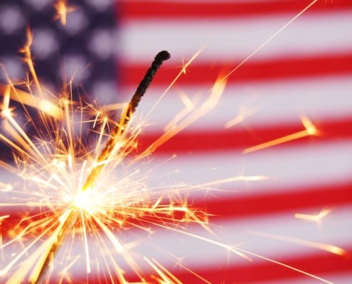 Sparkler lit up against an American Flag background