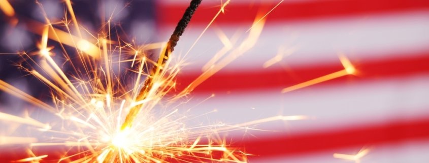 Sparkler lit up against an American Flag background
