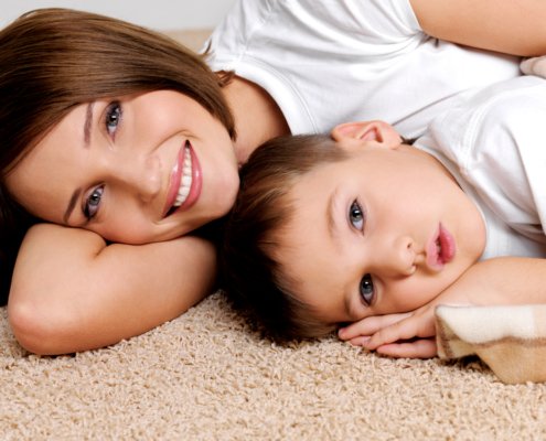 Mother laying on the carpet smiling with her son