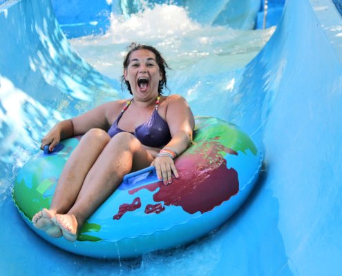 Smiling girl riding down a water slide using an inner tube