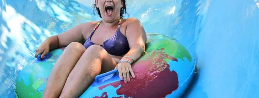 Smiling girl riding down a water slide using an inner tube