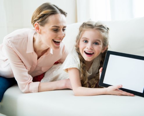 Mother and daughter on a couch holding a tablet