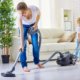 Mother vacuuming her floor as her daughter helps by holding the cord