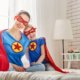 Mother and daughter dressed up as superheroes sitting in bed together