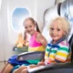 Two children smiling and sitting on a plane