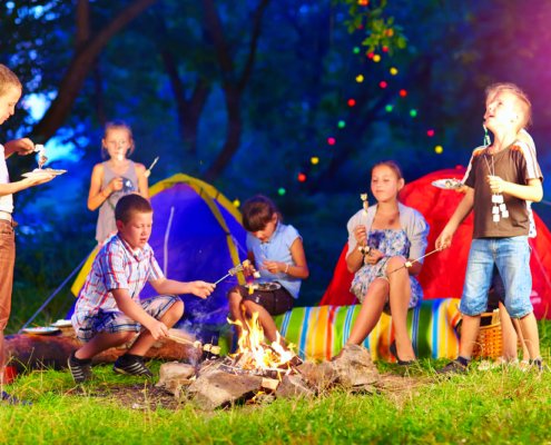 A group of kids roasting marshmallows around a campfire