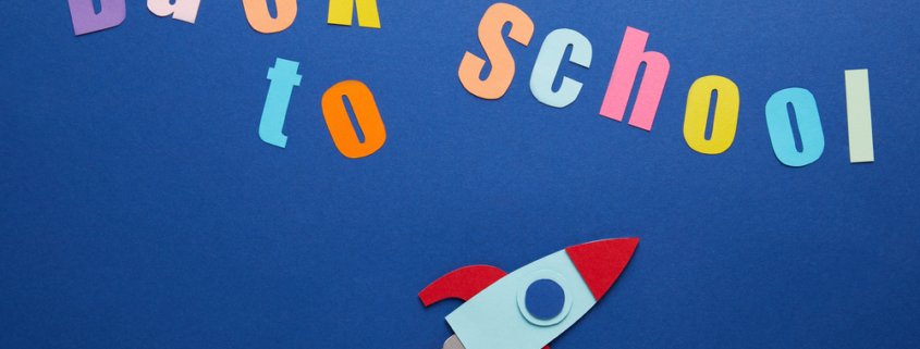 Colorful paper cut out to spell back to school with a rocket ship