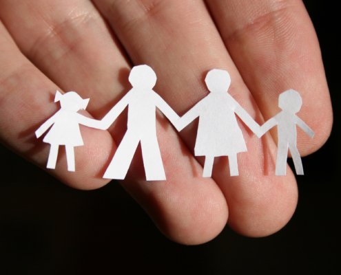 Hand holding a paper cut out of a family holding hands
