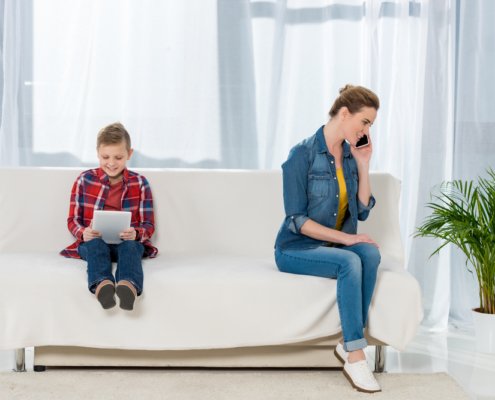 Mother sitting with her child on a couch while she is on the phone