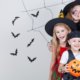 Three children dressed up as witches and a pirate for Halloween smiling together