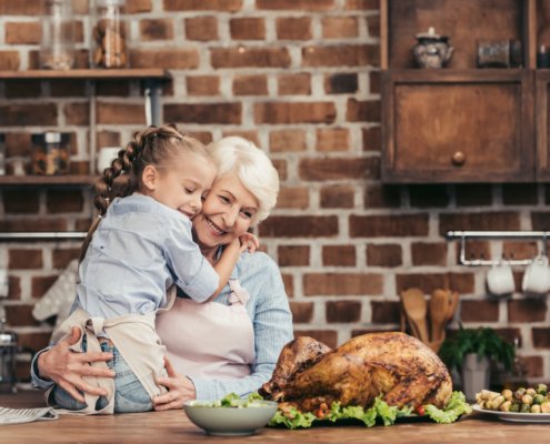 Grandmother and grandaughter smiling and hugging together over Thanksgiving dinner